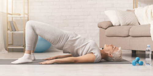 active-senior-woman-doing-back-exercise-on-floor-at-home
